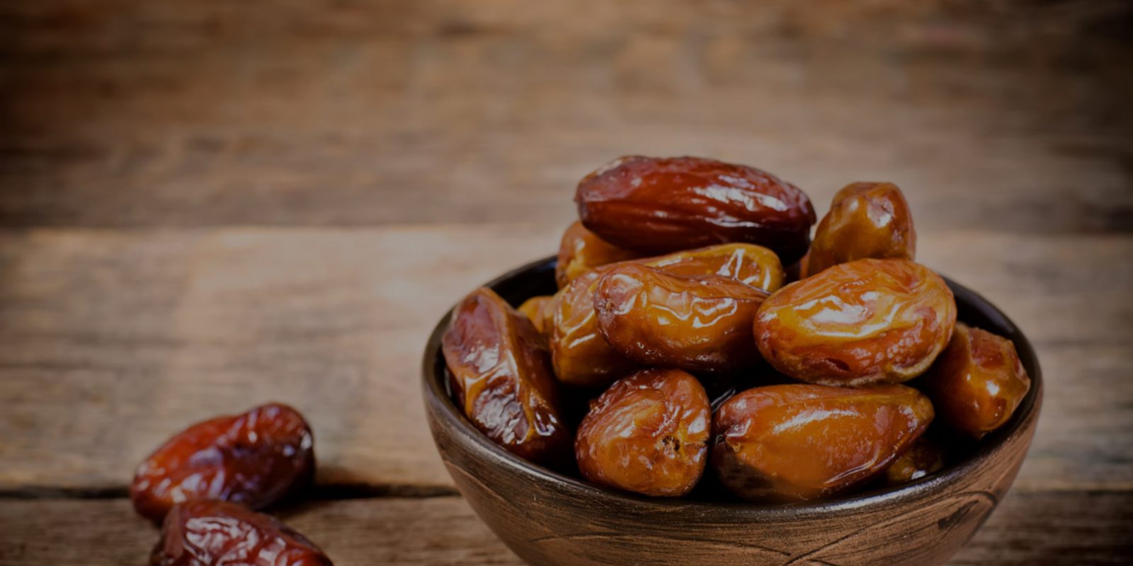 Bowl of Deglet Noor dates on a wooden table - semi-dry, translucent amber dates from Tunisia